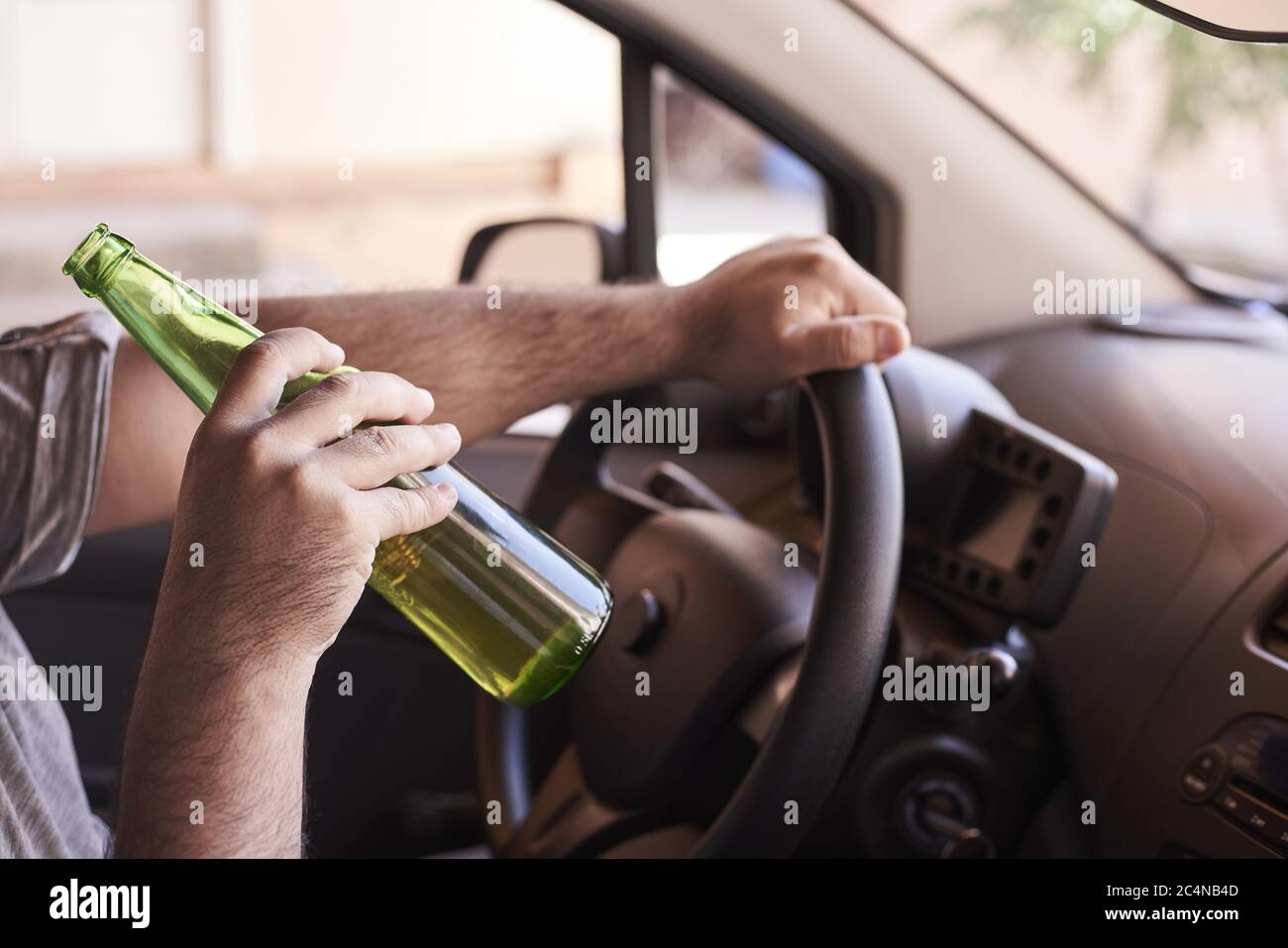 Bottle of beer in a man's hands driving the car during daytime Stock ...
