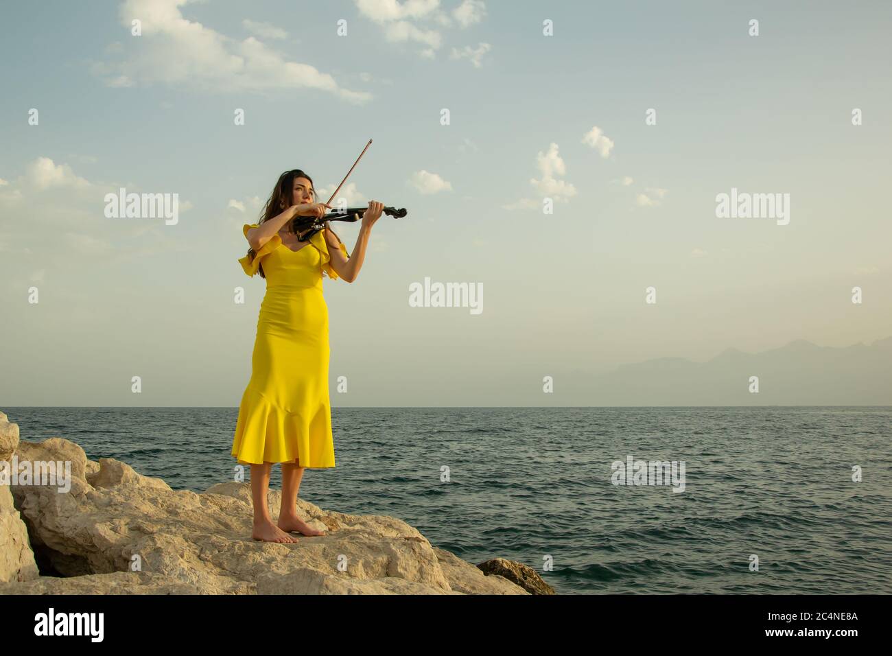 Beautiful violinist girl in yellow concert dress is playing electric