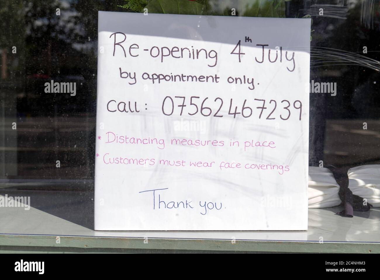 A sign in a hairdressers shop advertising appointments only from the 4th July 2020. Stock Photo