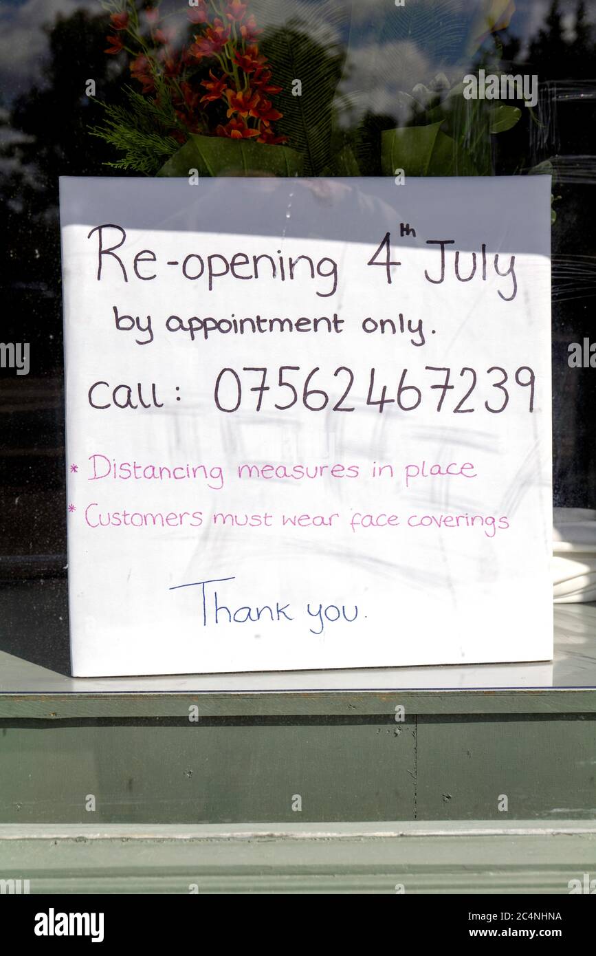 A sign in a hairdressers shop advertising appointments only from the 4th July 2020. Stock Photo