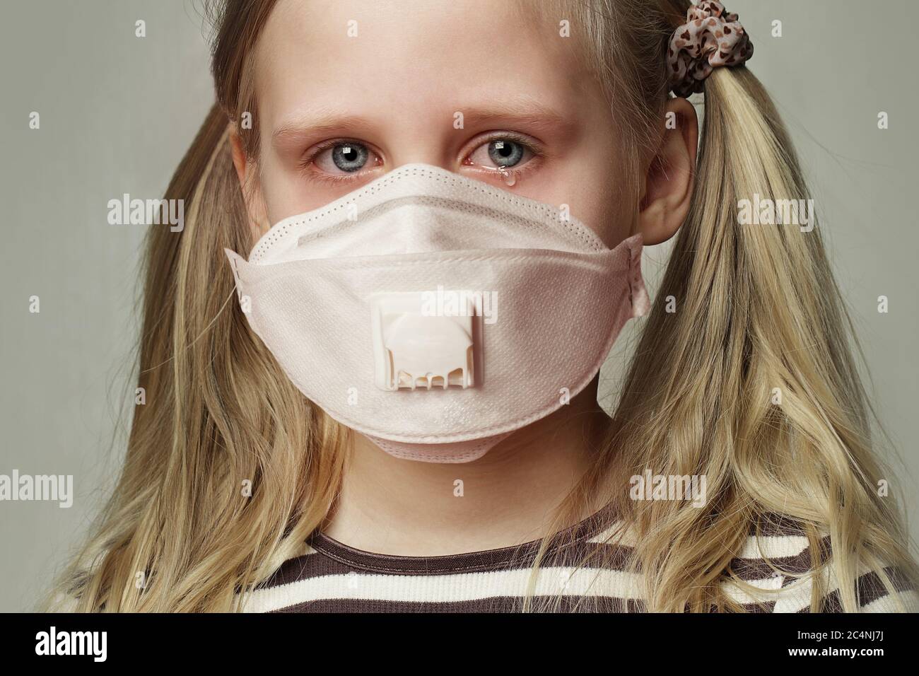 Child girl in protective medical mask crying, closeup portrait Stock Photo