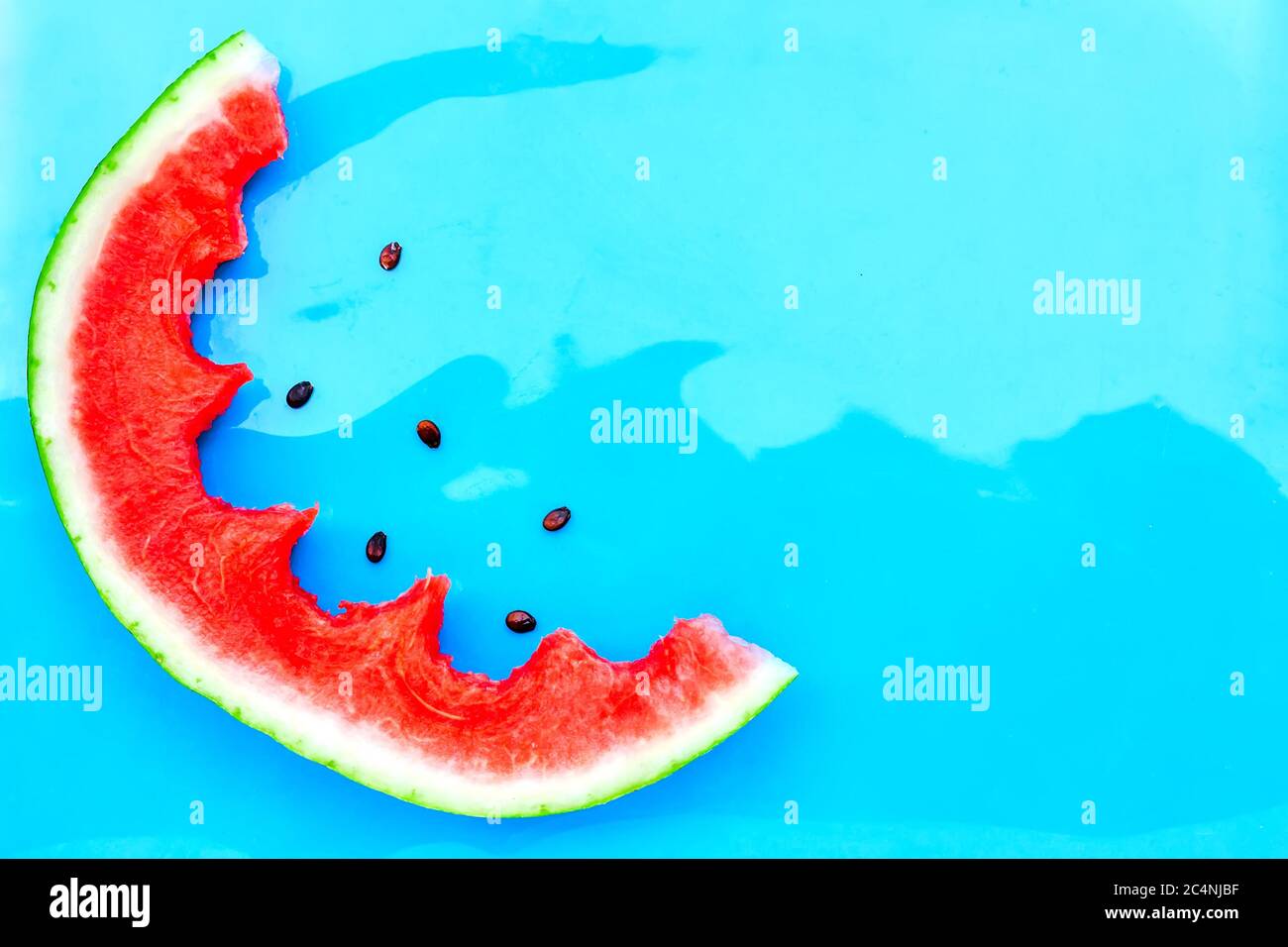 Summer creative watermelon layout. Bitten slice of fresh jucy watermelon on light blue background. Top view. Copy space Stock Photo