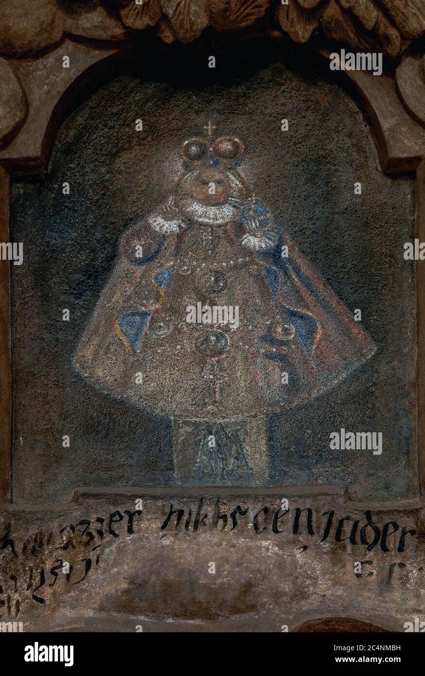 Faded painting of a 16th century wooden statue of Child Jesus, dressed in fine costume and with imperial regalia, known as the Infant of Prague.  Traditional house sign above a 1664 portal to an historic property, At The Blue Fox, now the Estonian Embassy, in Prague, Czech Republic or Czechia. Stock Photo