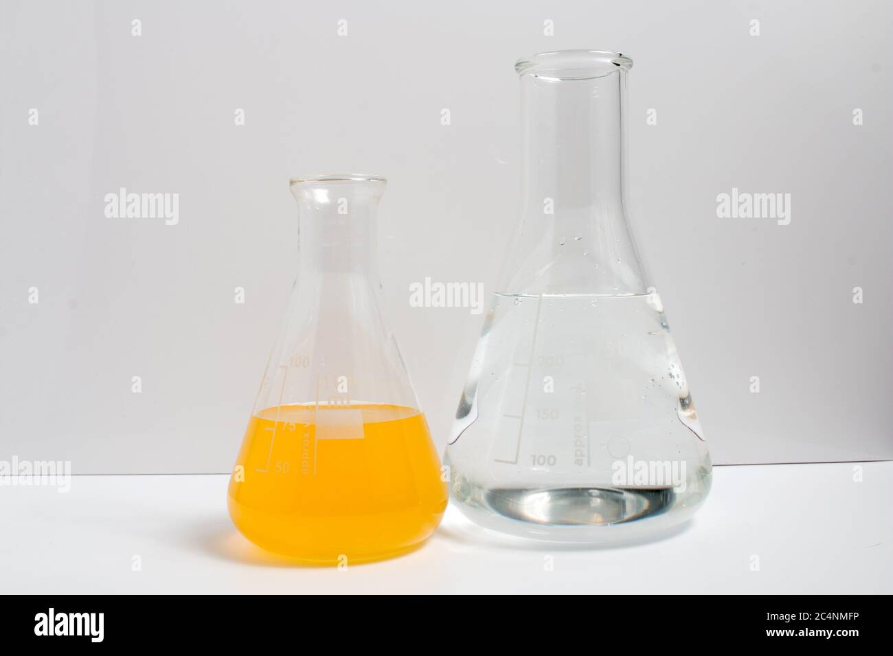 Laboratory glassware filled with chemical liquids on a white background ...