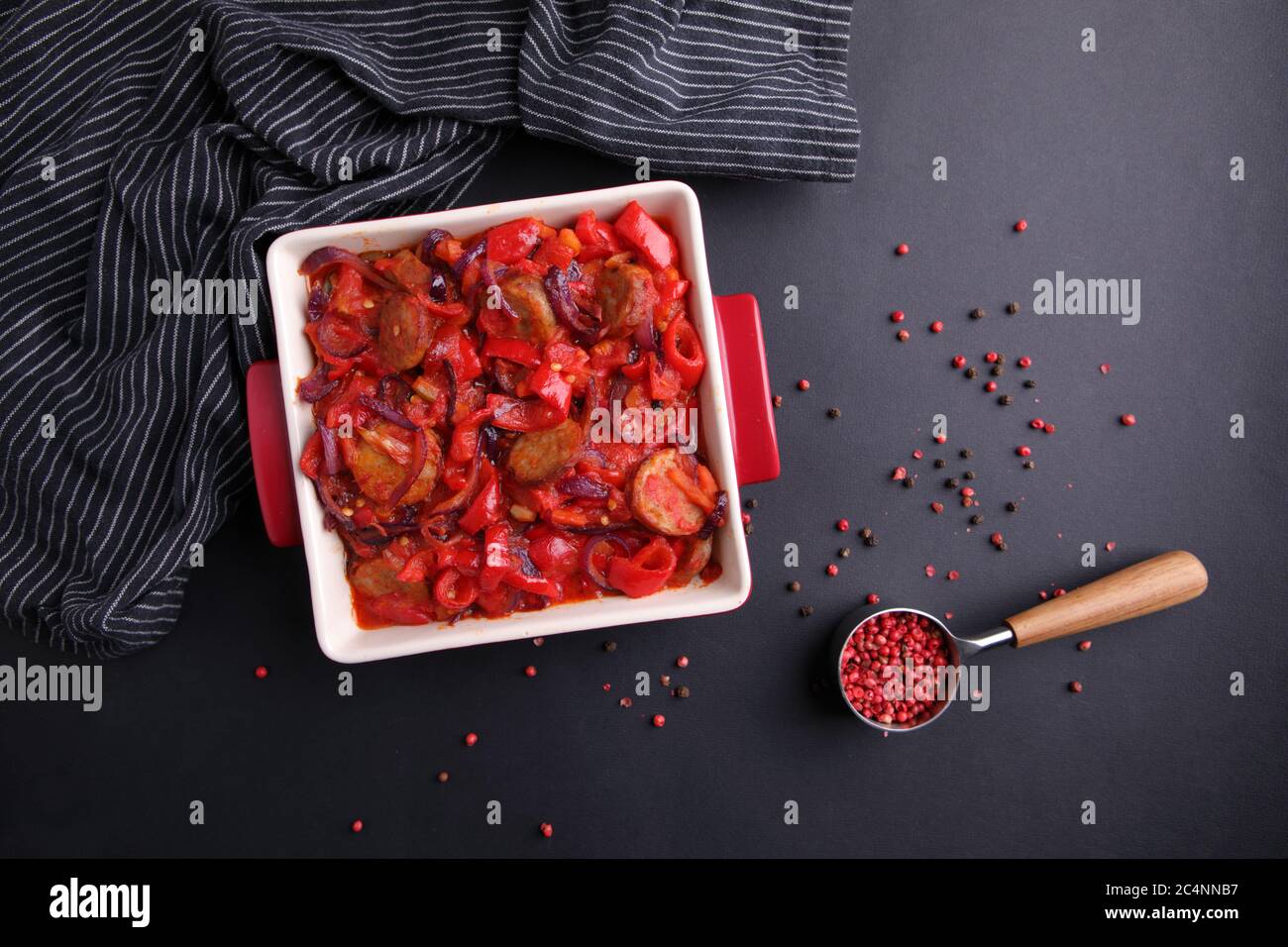 Traditional Hungarian tomato and red pepper stew with hungarian kolbasz sausages also known as Letcho or Lecso. Black background and low key lighting Stock Photo