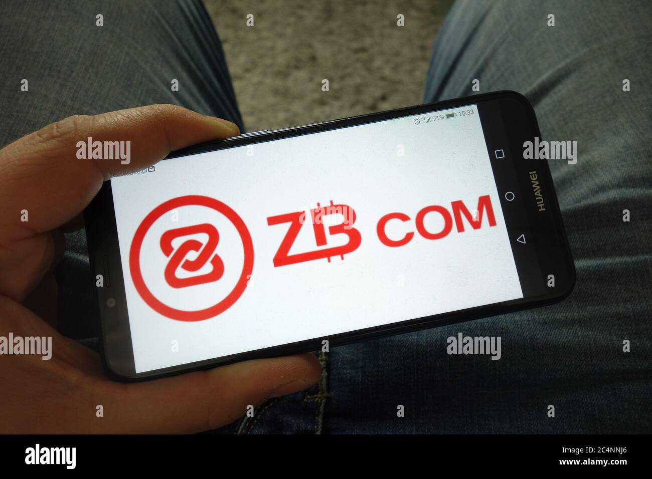 Man holding smartphone with ZB.COM cryptocurrency exchange logo Stock Photo