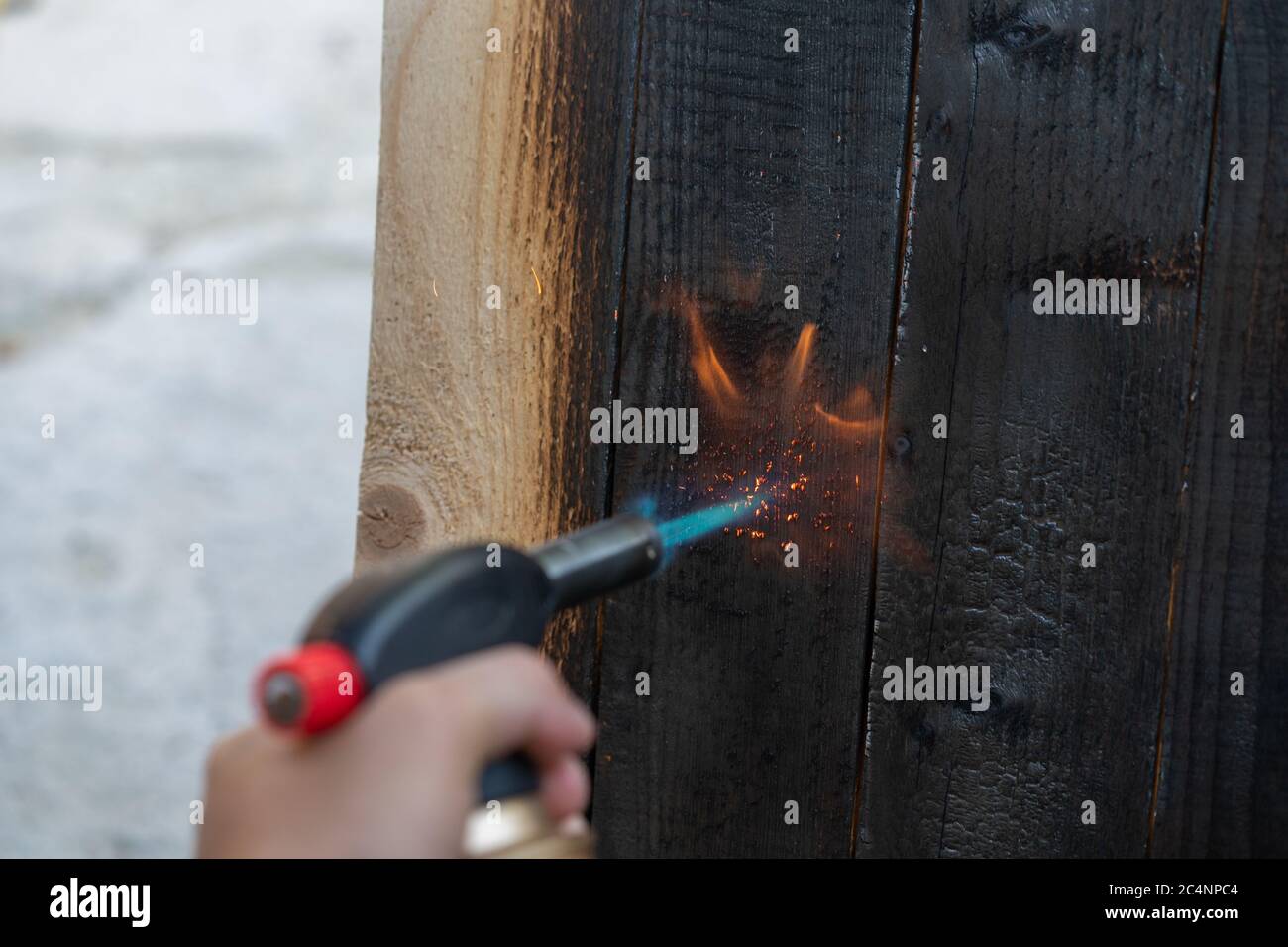 Professional carpenter using old traditional japanese technique. Burning wood planks with gas burner. DIY process. Stock Photo