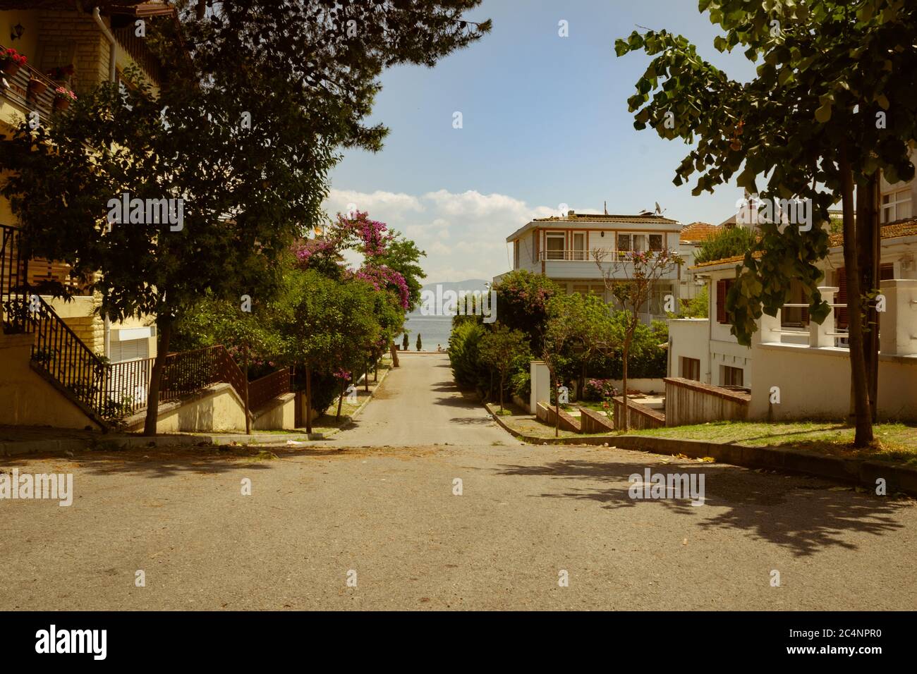 An empty street on island leading to the sea, beautiful sunny summer day. Stock Photo