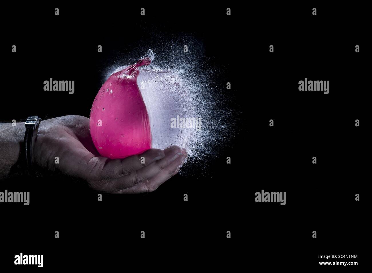Isolated shot of a water balloon exploding in the palm of a human hand