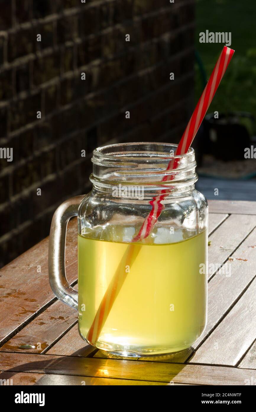Glass of orange squash with a straw on a table Stock Photo