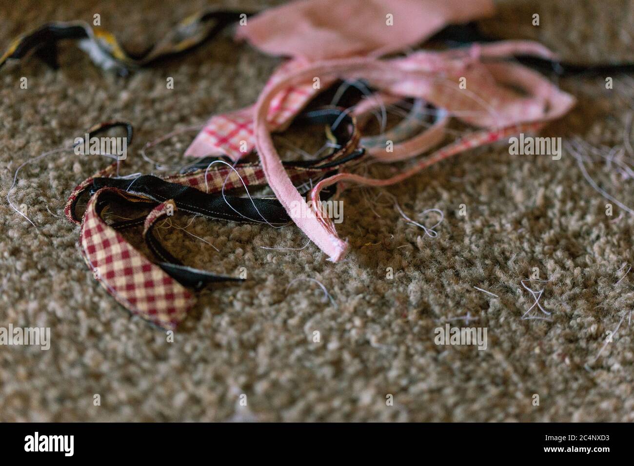Fabric scraps on floor black auburn gingham pink gingham white threads Stock Photo