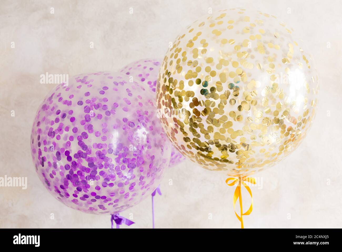 large round balloons. big balls with confetti. balls of gold and purple color Stock Photo