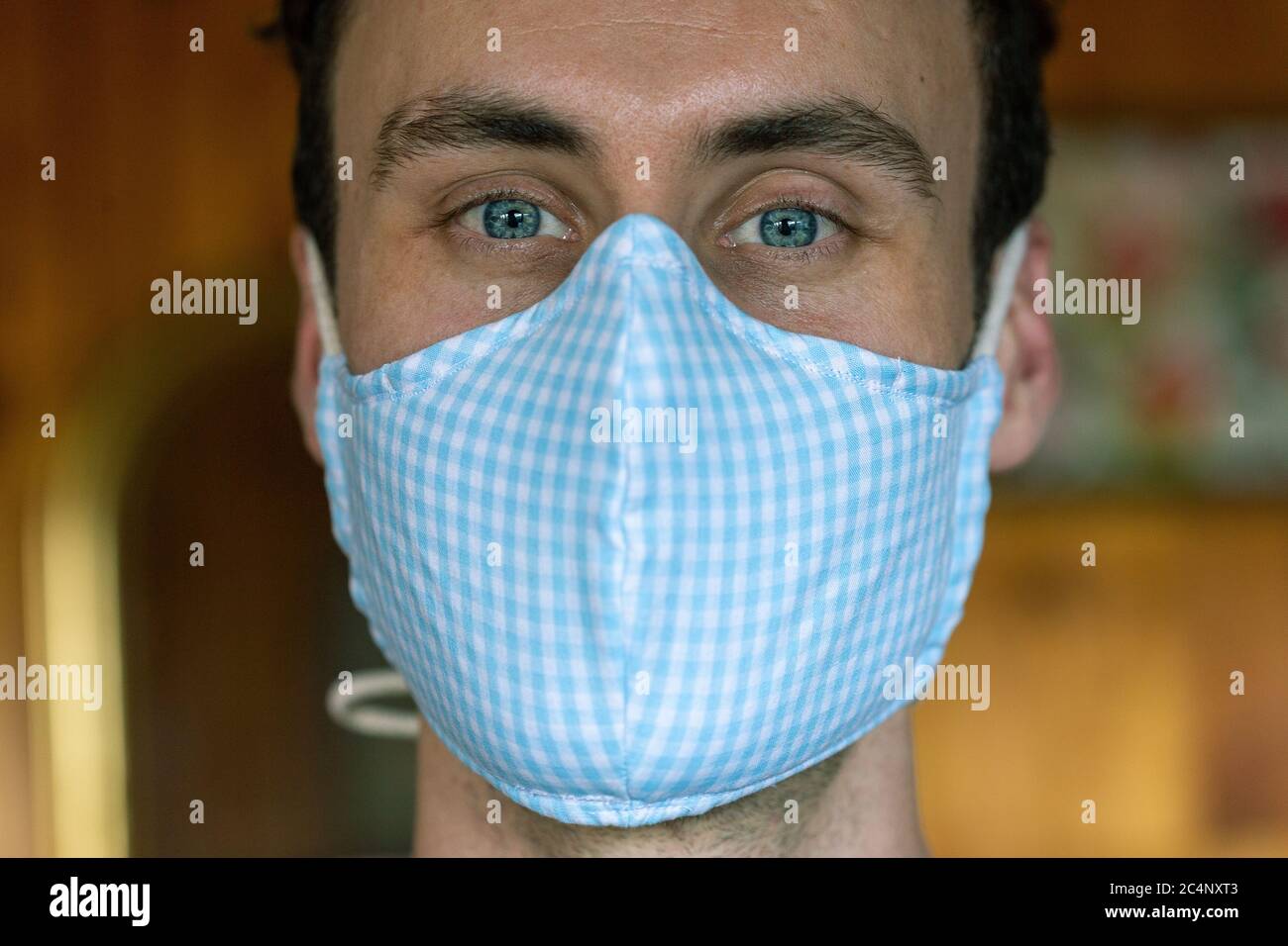 Young male donning deluxe fabric mask front good bone structure blue eyes strong jaw dark hair Stock Photo