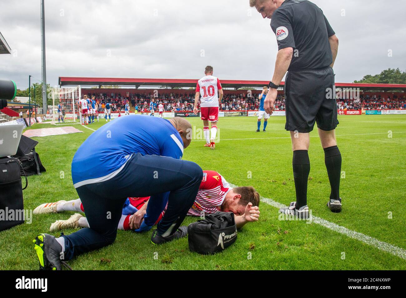 Football / soccer player receiving treatment from physio after getting injured during match at professional league game. Stock Photo