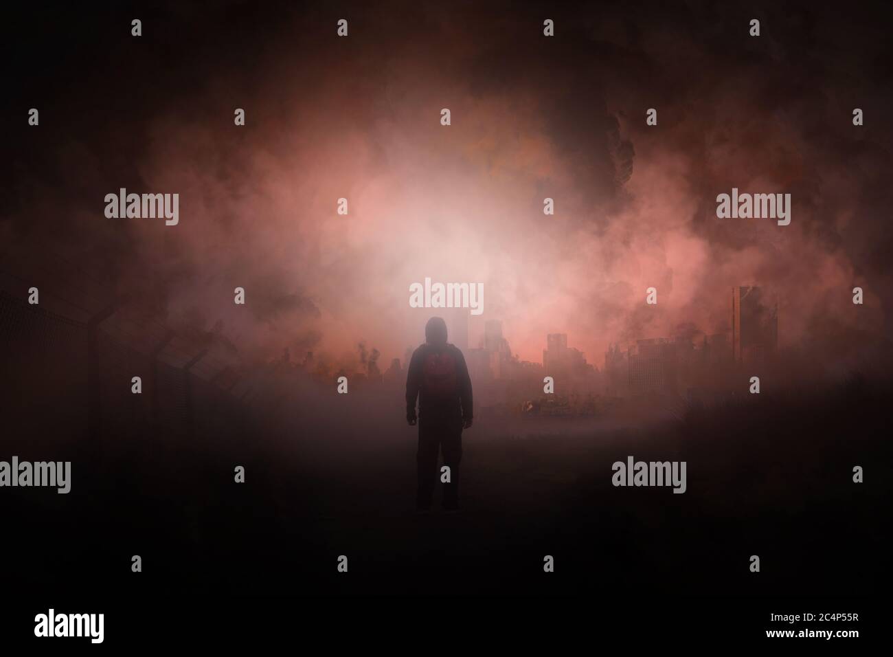 A post apocalypse scene showing a man standing in a ruined city looking at a destroyed city. With smoke covering the sky. Stock Photo