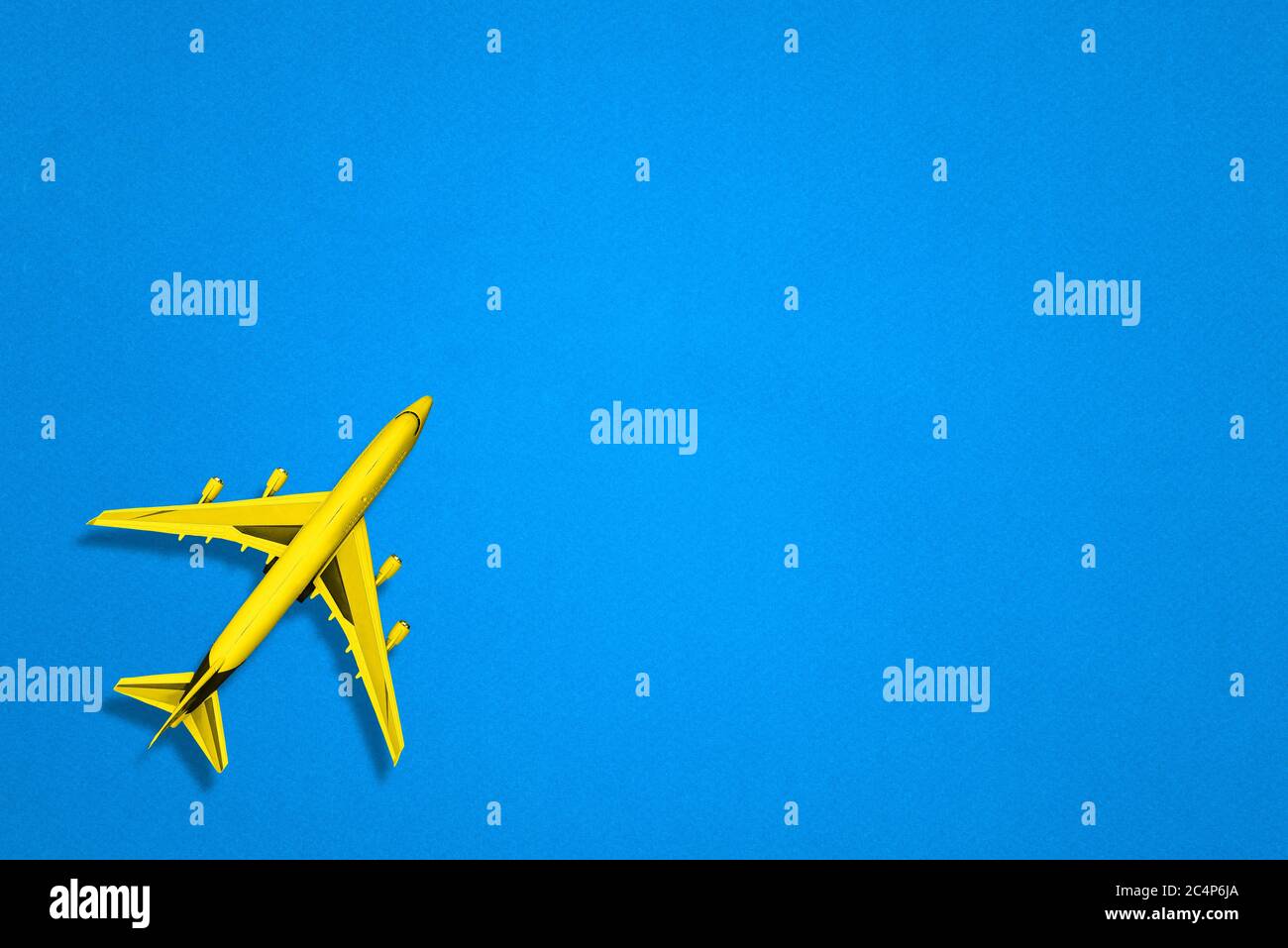 Yellow passenger plane on a blue paper background. A vehicle for delivering people, parcels, and other cargo. The concept of logistics and travel. A Stock Photo