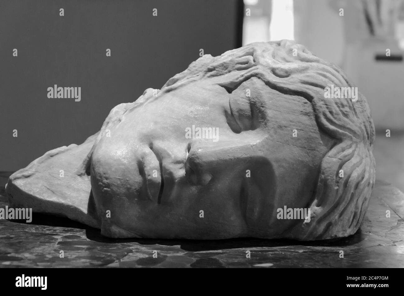 Black and white photo in close-up of face of ancient roman marble sculpture showing a young man sleeping Stock Photo