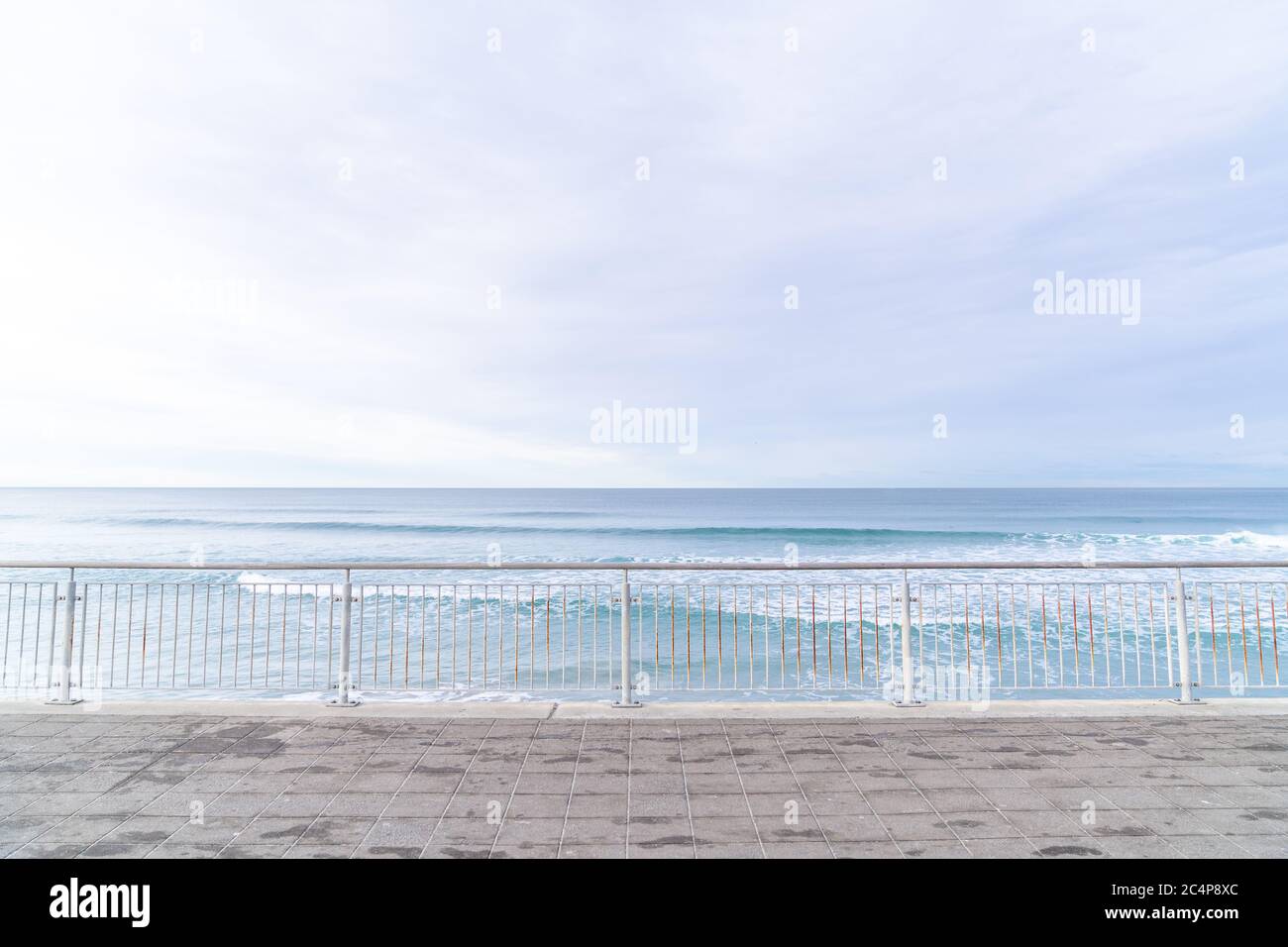 Soft blue ocean wave on sandy beach with metal fences. Background textured. Stock Photo