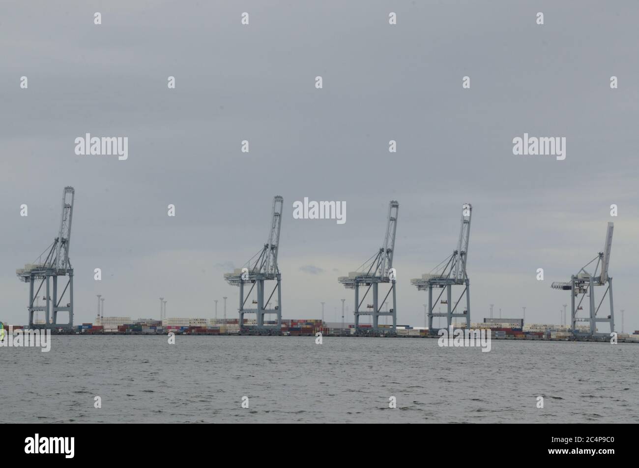 Five large container cranes at Aarhus container port in Denmark in the background Stock Photo