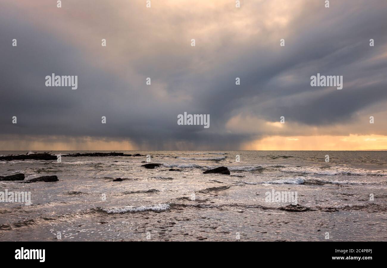 A backlit winter rain storm out to sea on the English coast Stock Photo