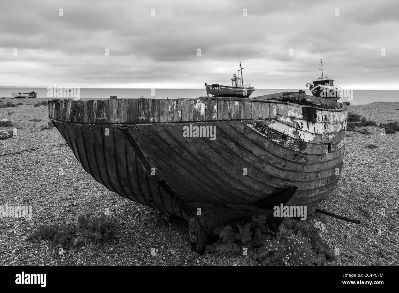 The wreck of an old wooden fishing boat on the shingle beach at ...