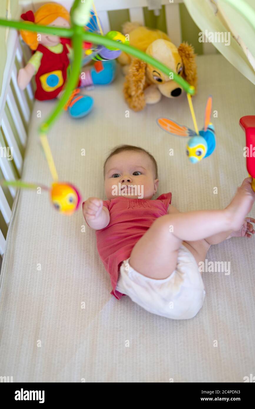 Baby girl lying in cot hi-res stock photography and images - Alamy