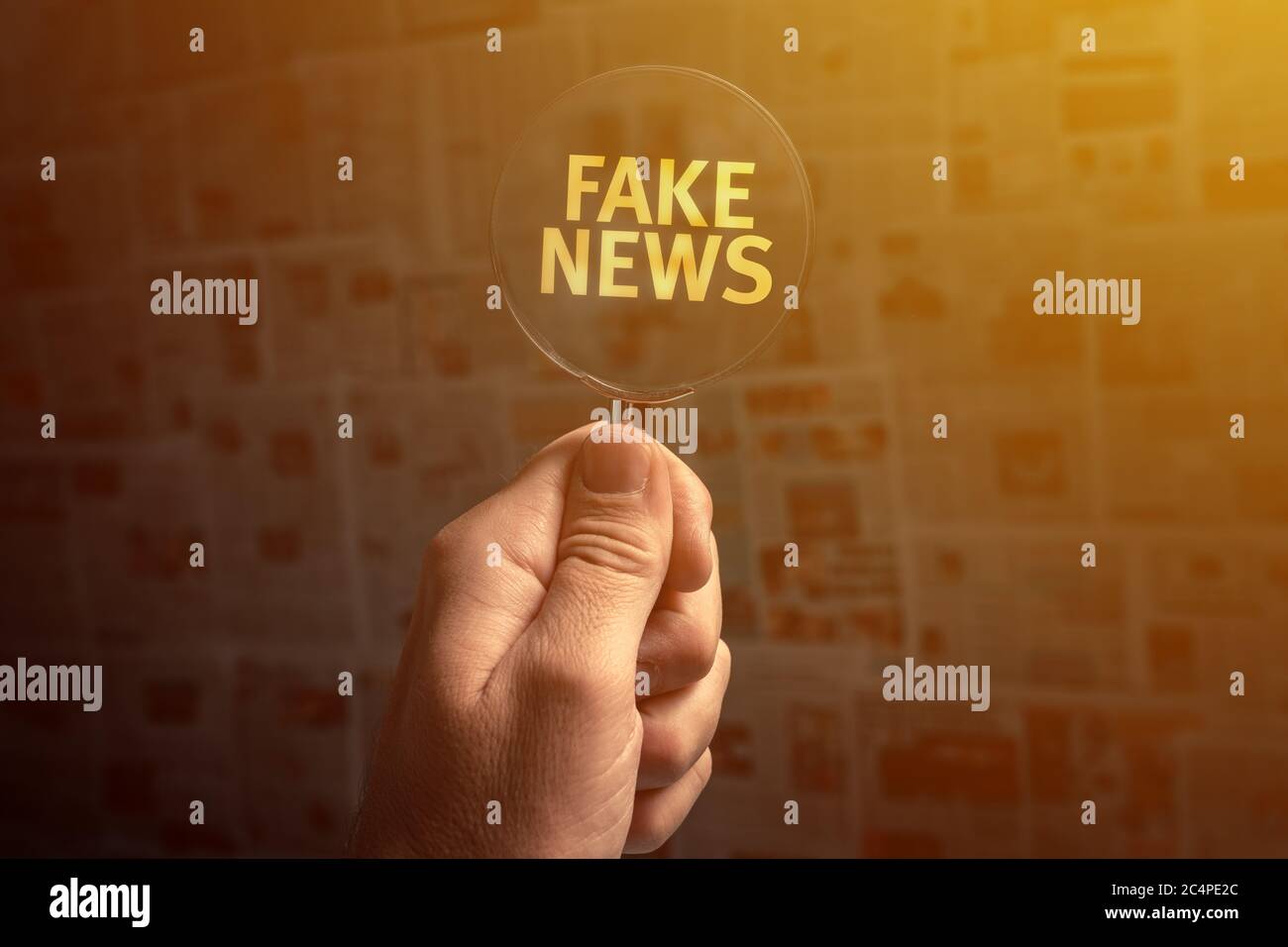 Fake news seeker, male hand with magnifying glass Stock Photo
