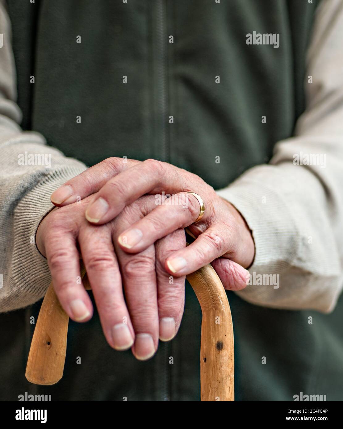 Old man resting on a wooden walking stick Stock Photo