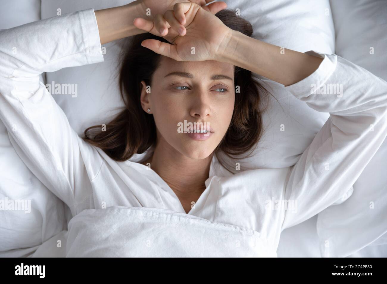 Depressed woman lying in bed feeling down or upset Stock Photo