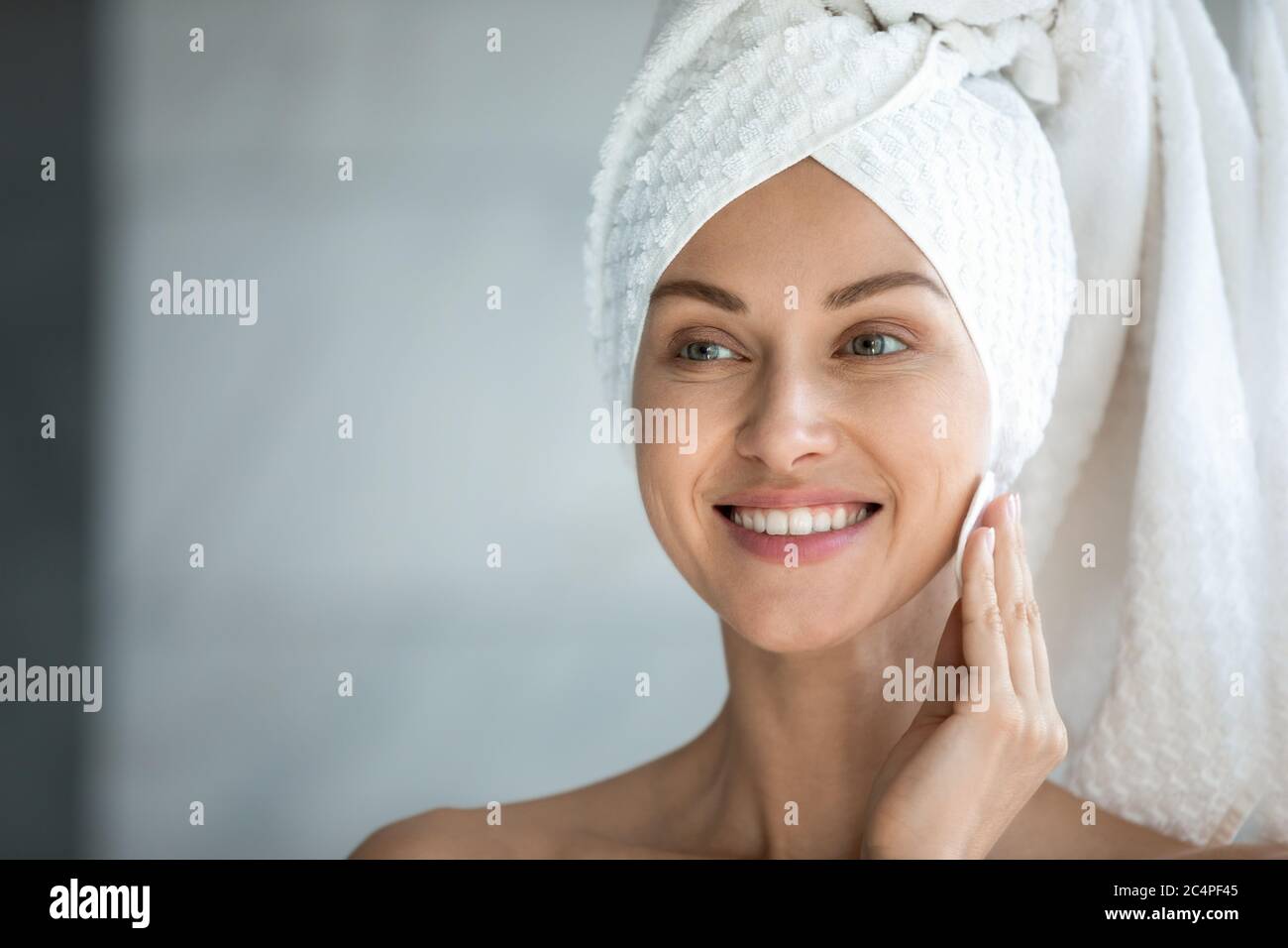 Smiling young woman look in mirror do facial beauty procedures Stock Photo
