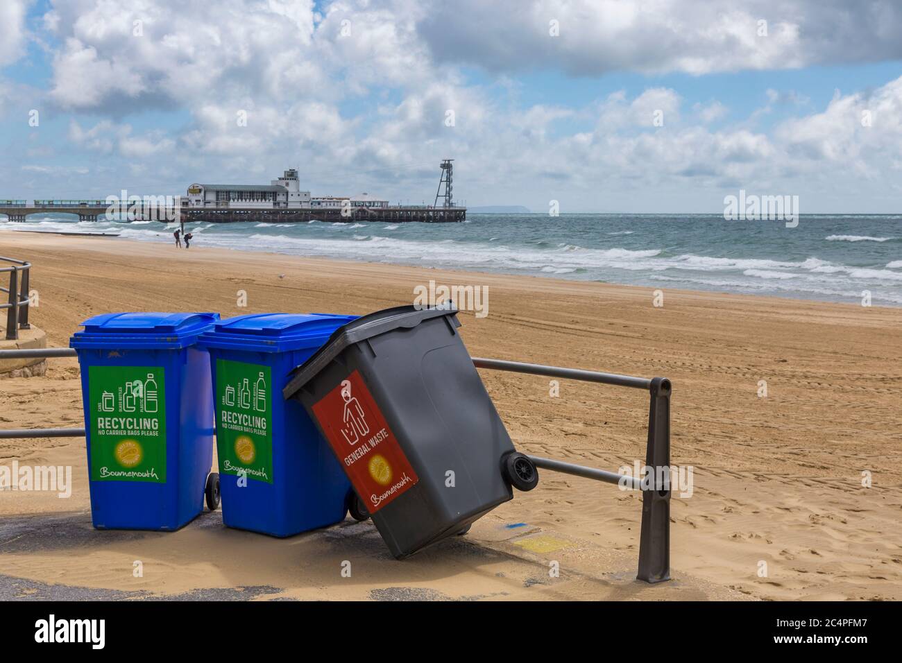 Rubbish bins, 2 recycling and one for general waste leaning over, on promenade at Bournemouth