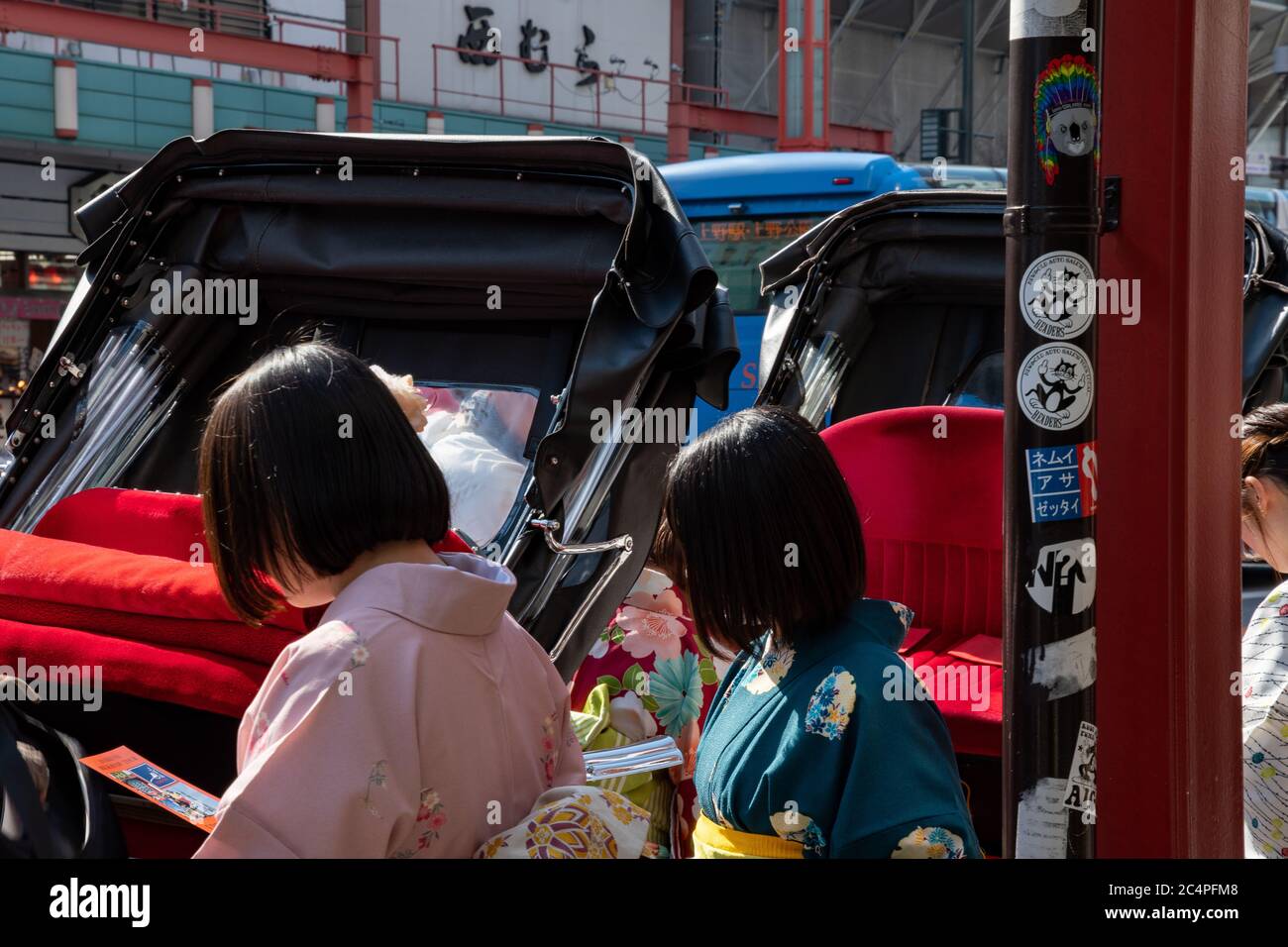 Young Japanese tourists wearing traditional kimono, taking a rickshaw for a sightseeing tour in Asakusa temple area.Tokyo, Japan. Stock Photo