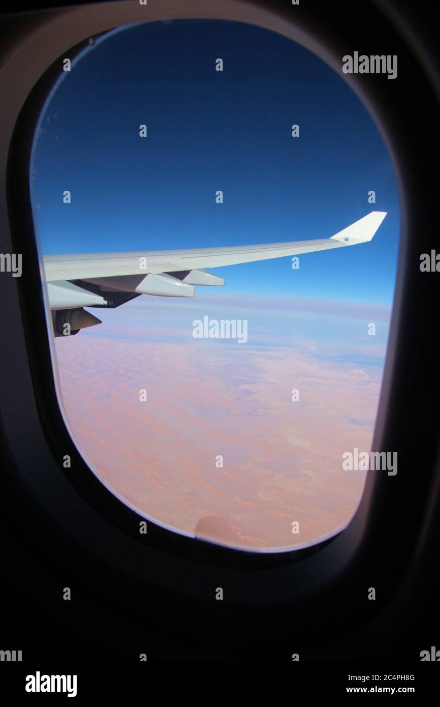 On a flight over the Sahara desert. Wing of the airplane and desert landscape far below. Africa. Stock Photo
