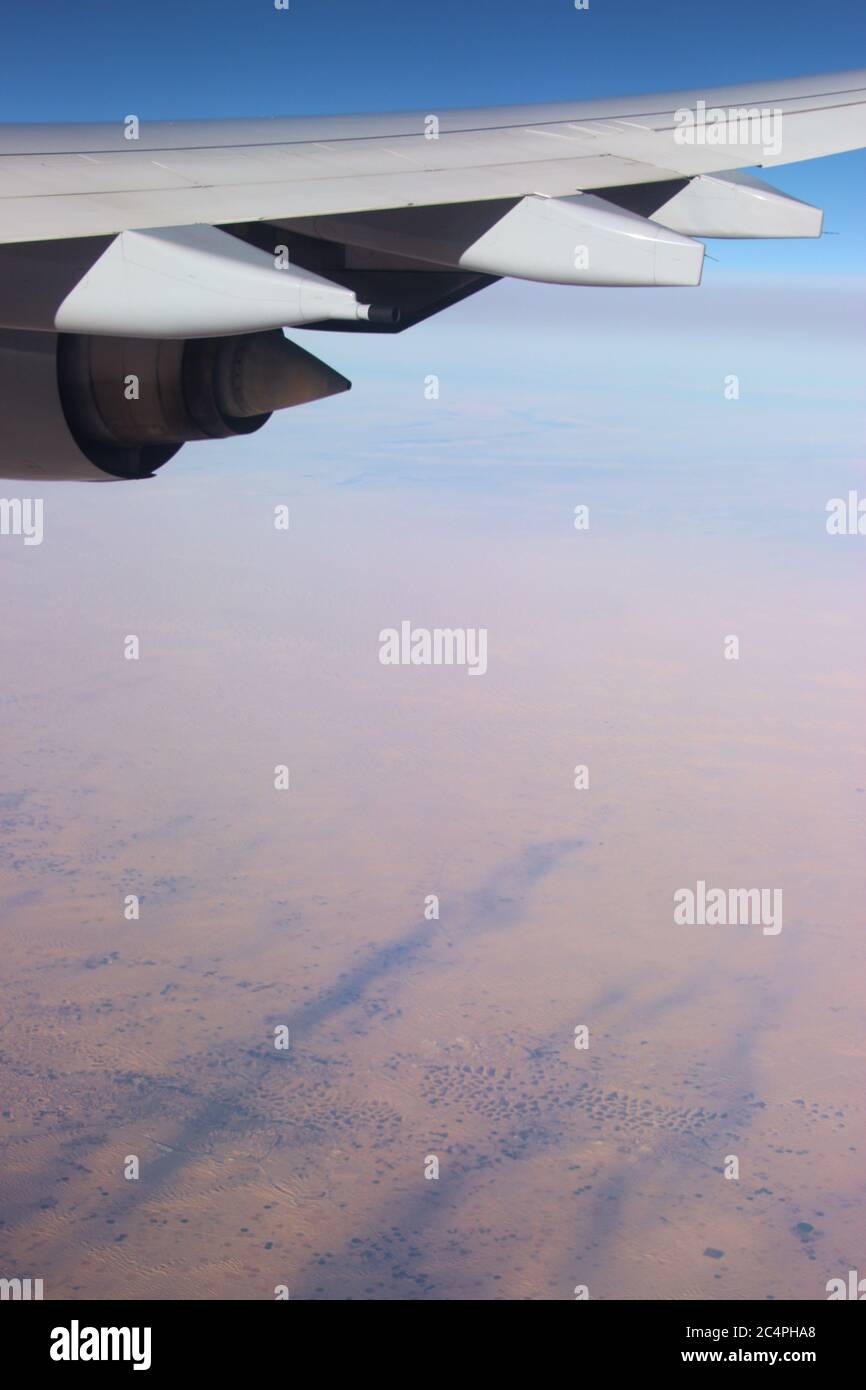 On a flight over the Sahara desert. Wing of the airplane and desert landscape far below. Africa. Stock Photo