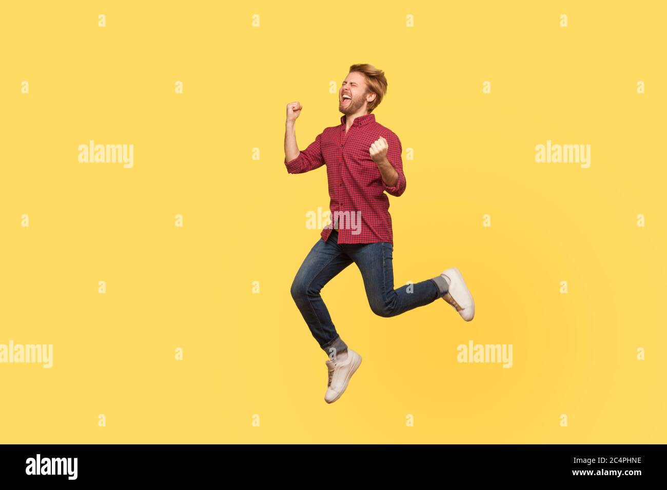 Enthusiastic overjoyed victorious guy in casual outfit jumping high trampoline, flying in air shouting for joy, celebrating victory. Life people energ Stock Photo