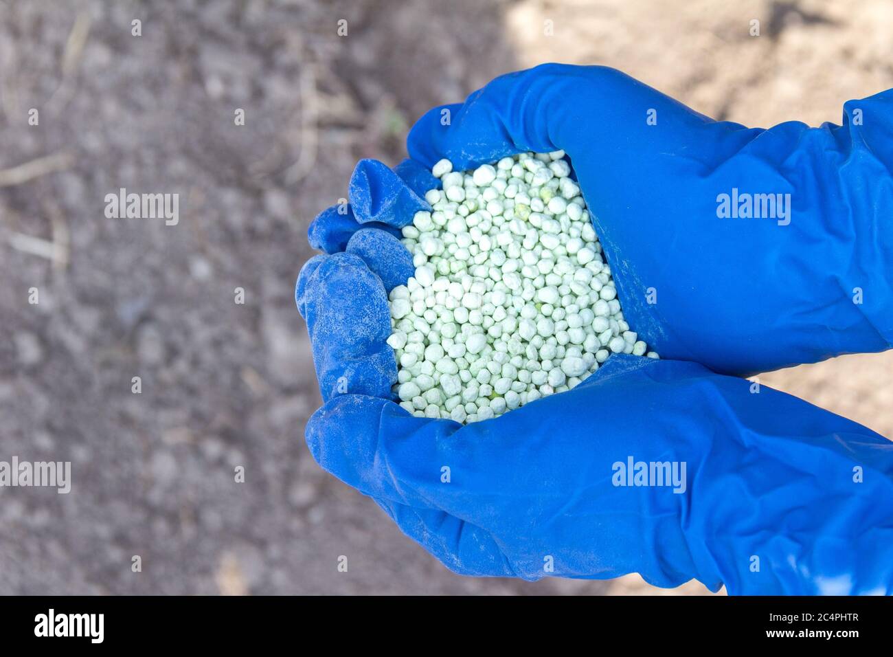 Green different shape chemical fertilizer granules in human's hand. Stock Photo