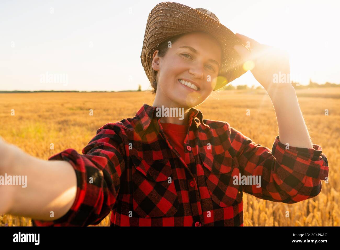 Woman farmer makes selfie on the background of a wheat field. Stock Photo