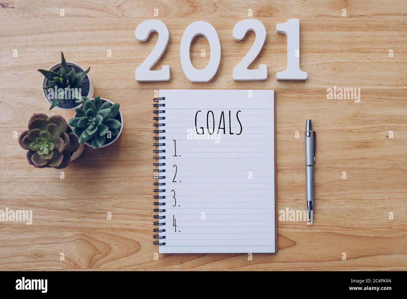 New year 2021 goals list. Office desk table with notebooks and pancil with pot plant. Stock Photo