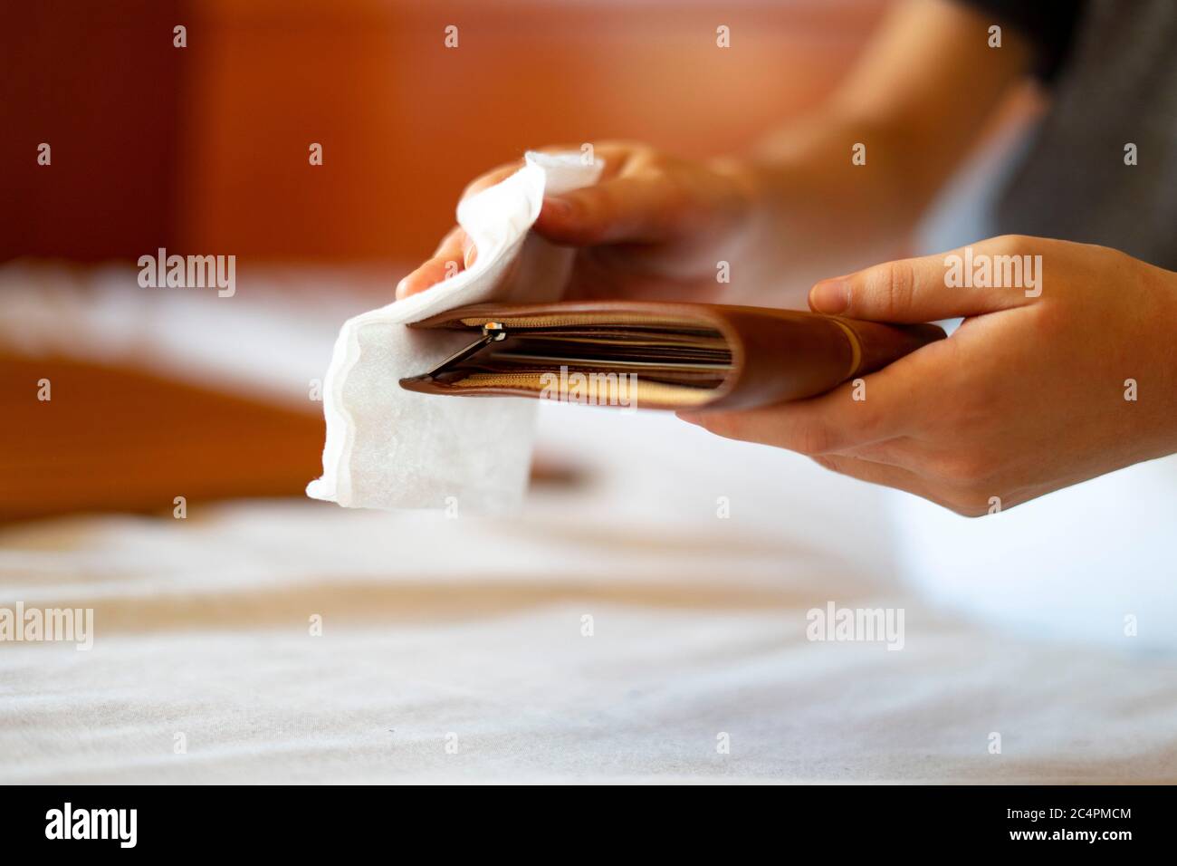 Man disinfecting his wallet with a disinfecting wipe. Concept of disinfecting a wallet. Stock Photo