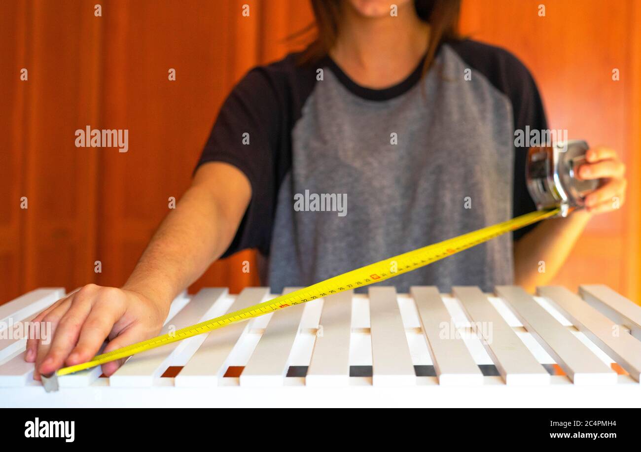 Woman measuring a piece of furniture with a tape measure. Tape measure