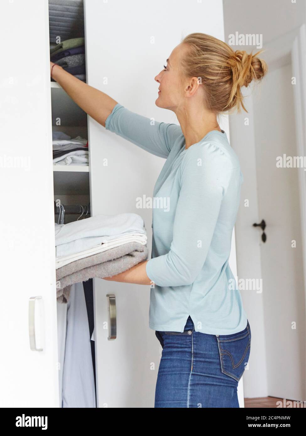Woman putting away laundry UK and Irish rights only. EDITORIAL USE ONLY Stock Photo