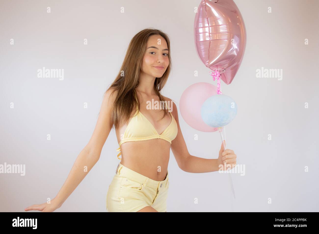 Pretty young girl in bikini catching colored balloons Stock Photo