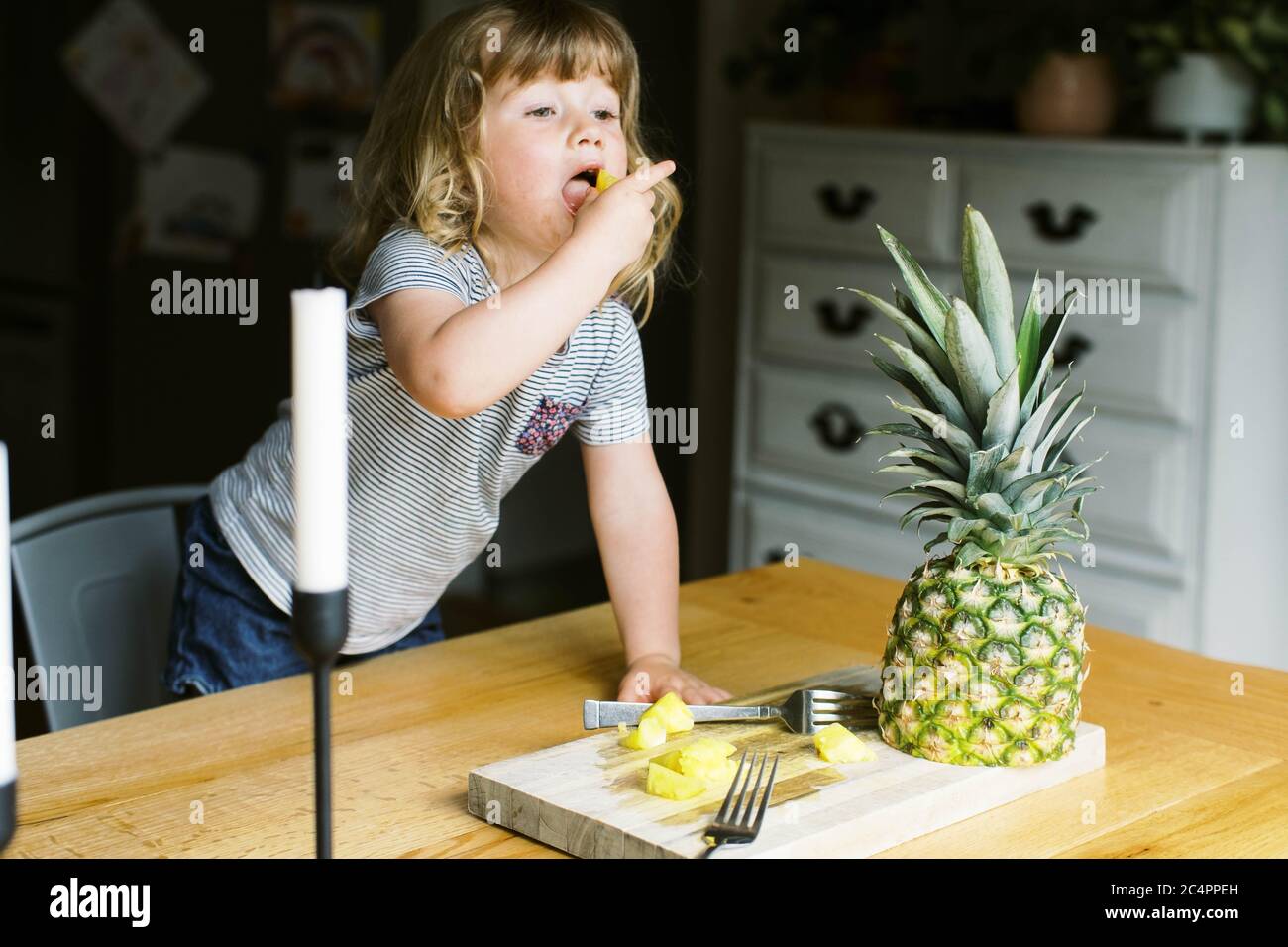 A little toddler girl having a healthy pineapple snack Stock Photo