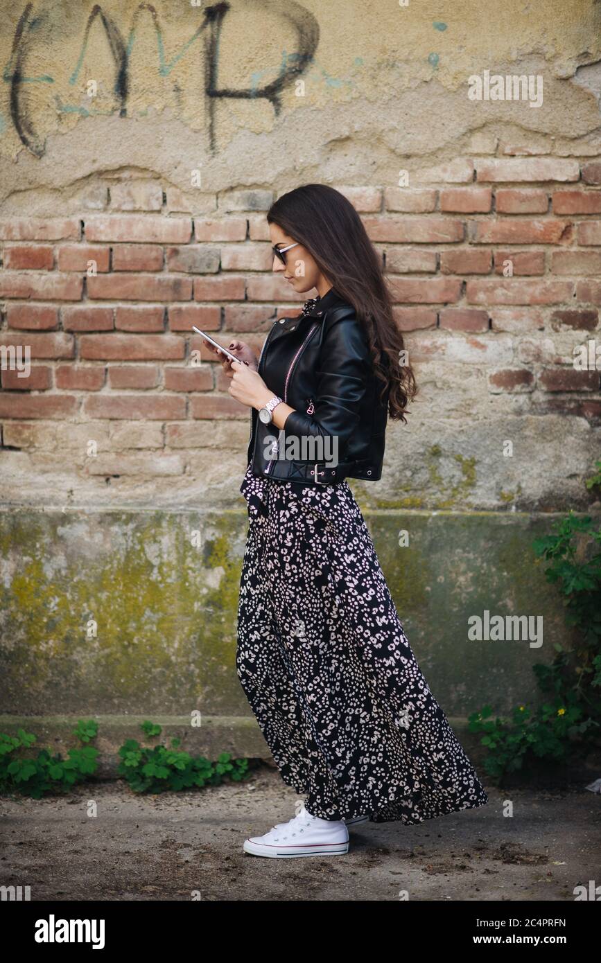 Attractive lady in dress is looking at phone outside. Stock Photo