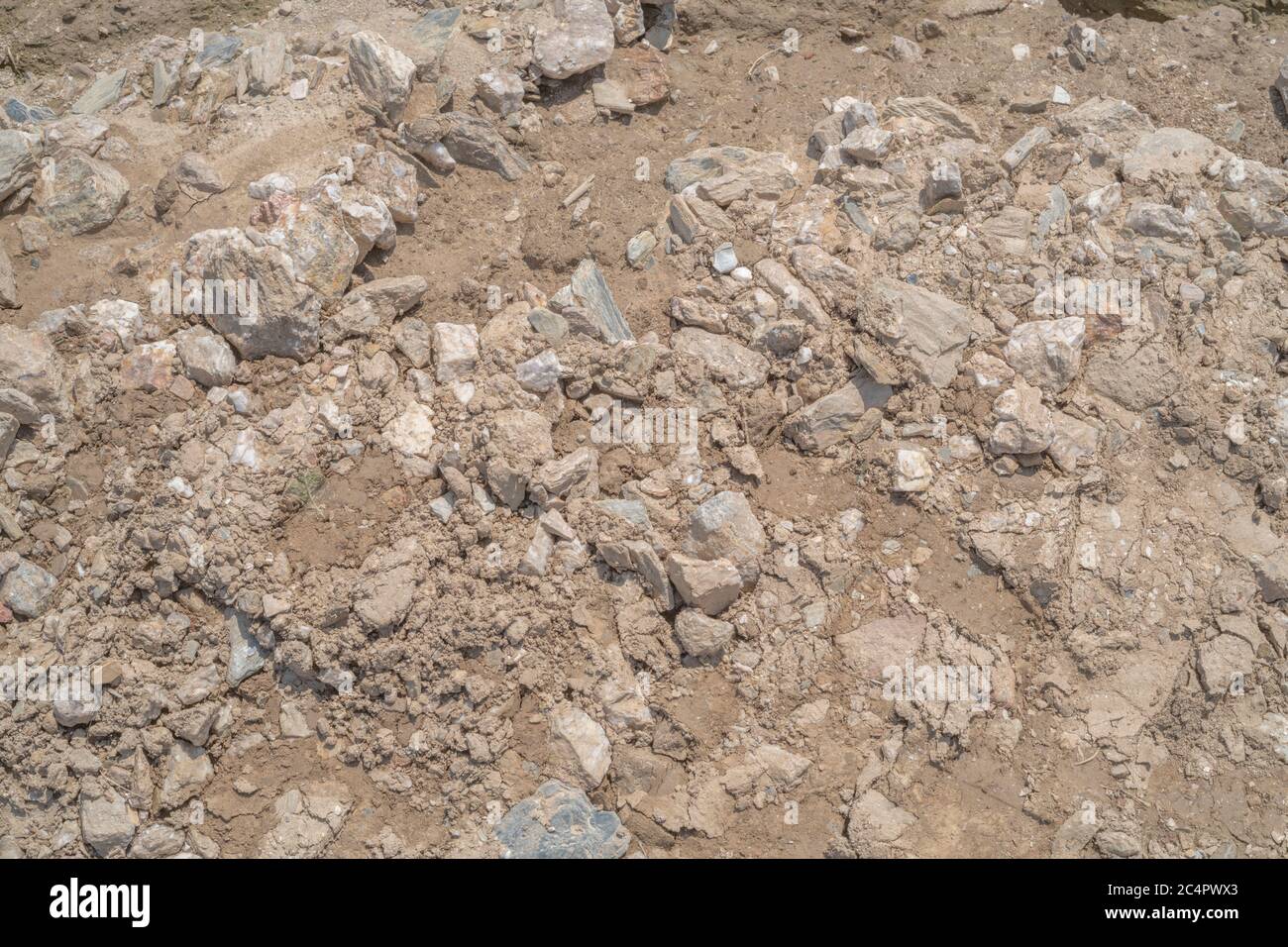 Exceptionally dry stony soil in sunlit field, left behind flash flooding of cropped field. Soil texture, soil structure, random concept, bad ground. Stock Photo