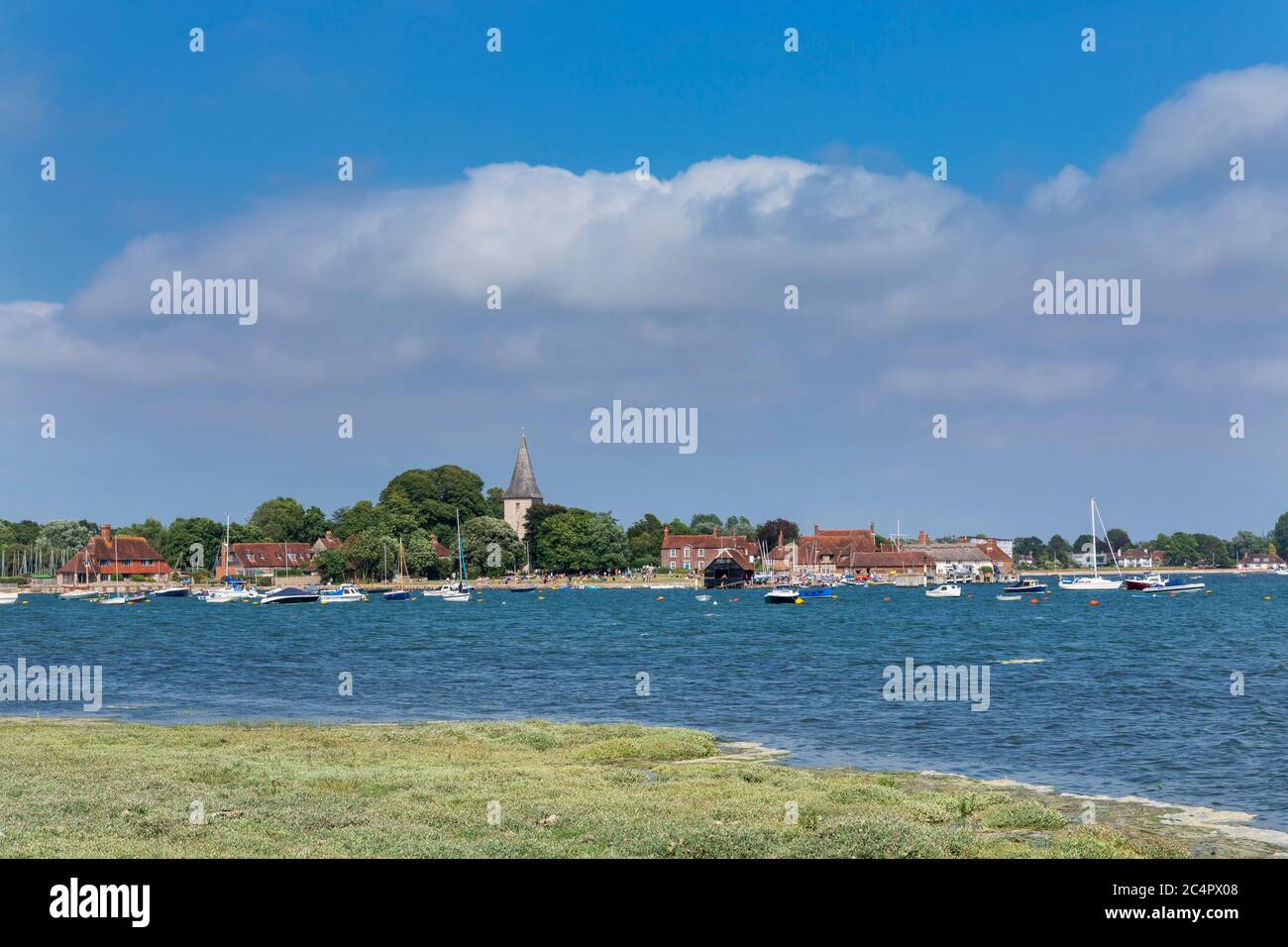 High tide Bosham in West Sussex across Chichester habour on a summers day. Distant shot of the village with large expanse of water in front. Stock Photo