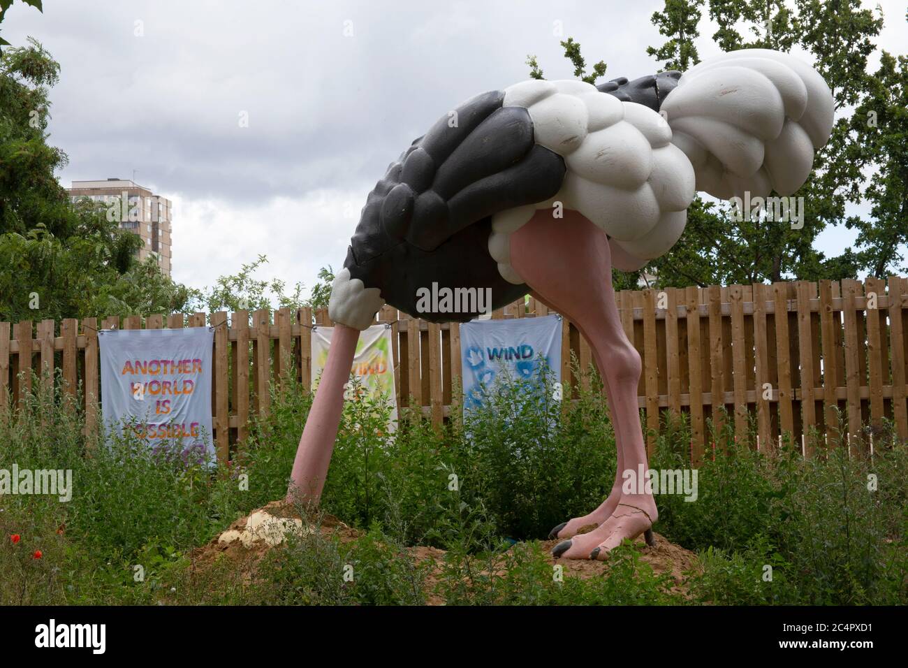 An Extinction Rebellion ostrich statue with its head in the sand in the Community Garden in White City Shepherd's Bush London W12 UK Stock Photo