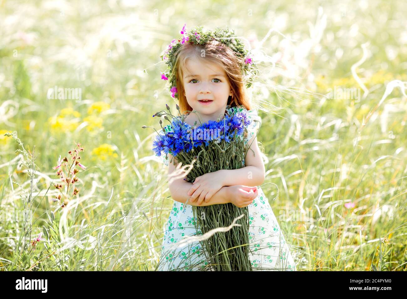 portrait of a cute little girl with a wreath on her head smiling ...