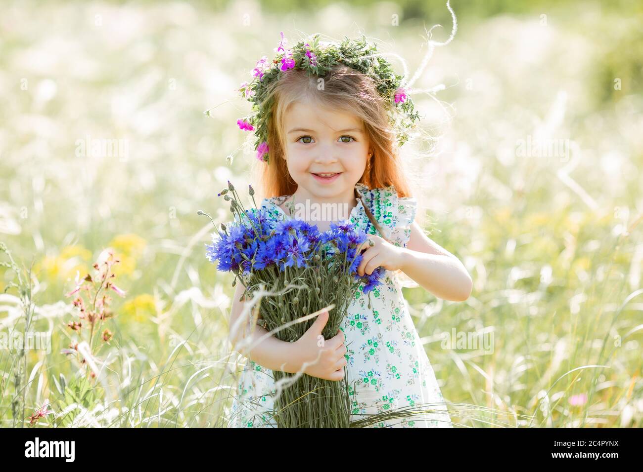 portrait of a cute little girl with a wreath on her head smiling ...