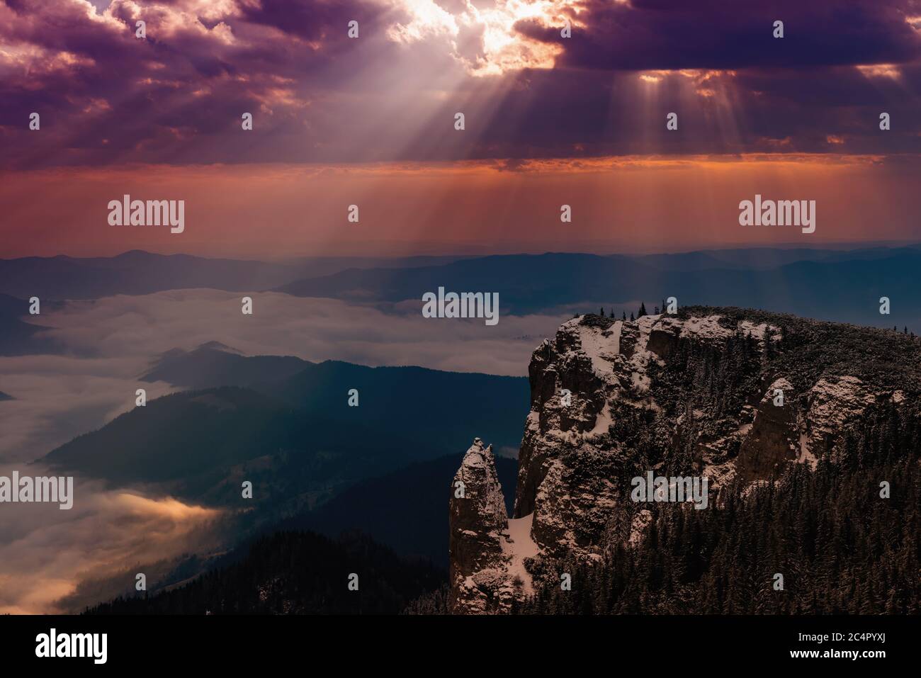 sunrise on the snowy mountains and the sun's rays pass through the clouds Stock Photo